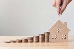 coins building up into a house piggy bank