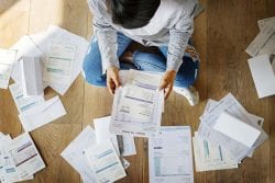 person sitting on floor looking over bills and finances