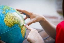 person pointing to a spot on a globe